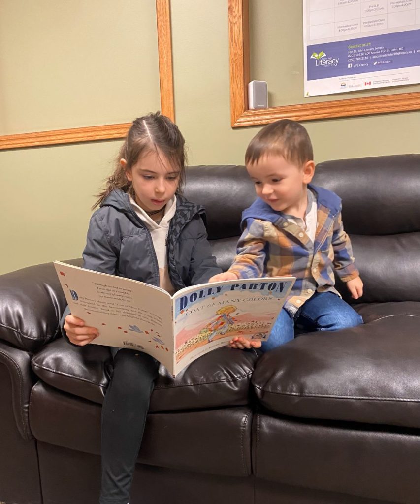 Brother and sister sharing a book.